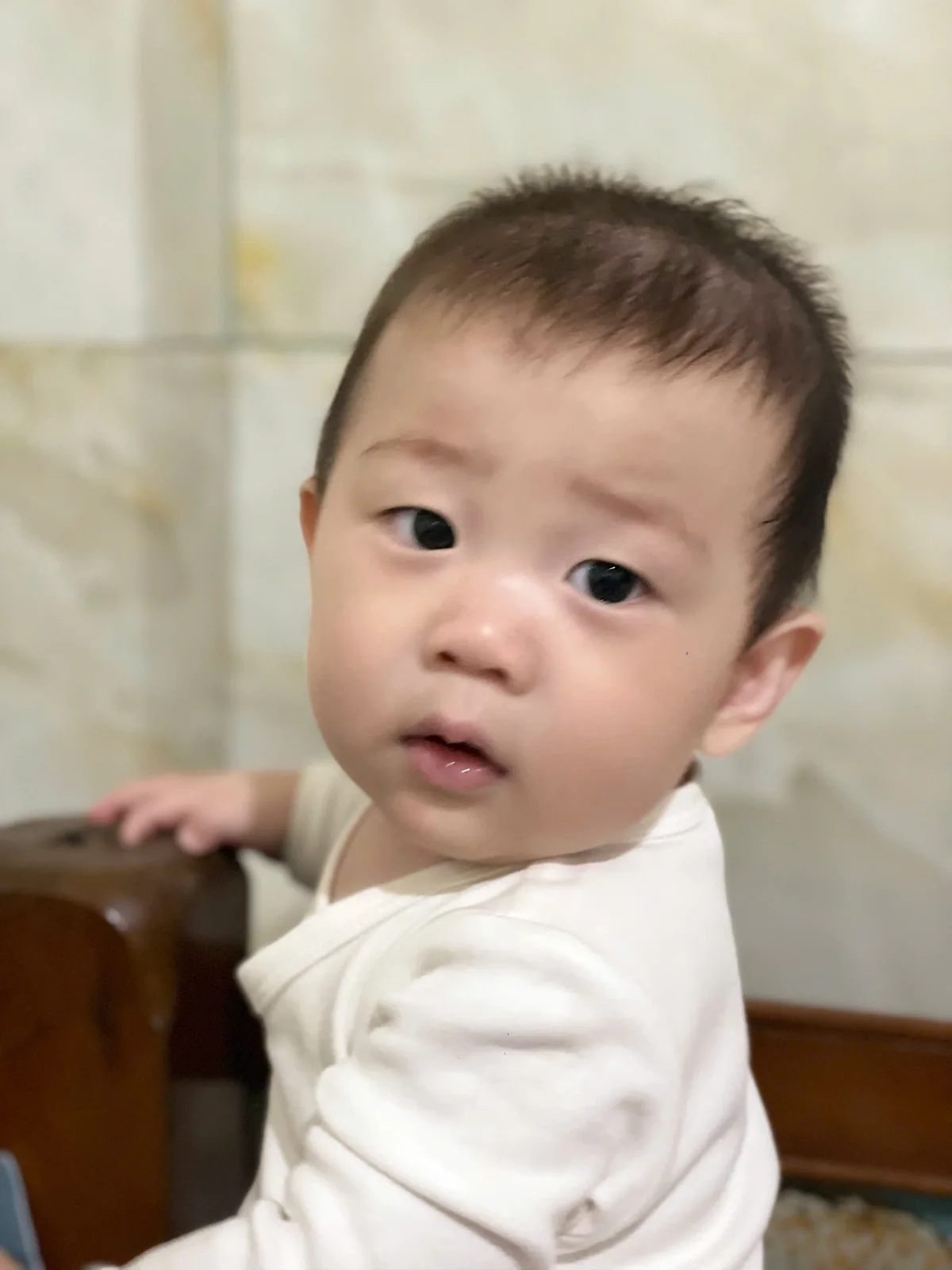 Bé Tú Tài mặc áo trắng, đôi mắt tròn nhìn về phía máy ảnh
